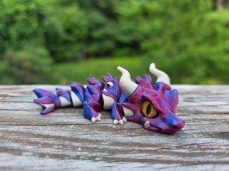 Mudrak flexi dragon, a fully articulated 3D printed dragon, posed coiled on a desk